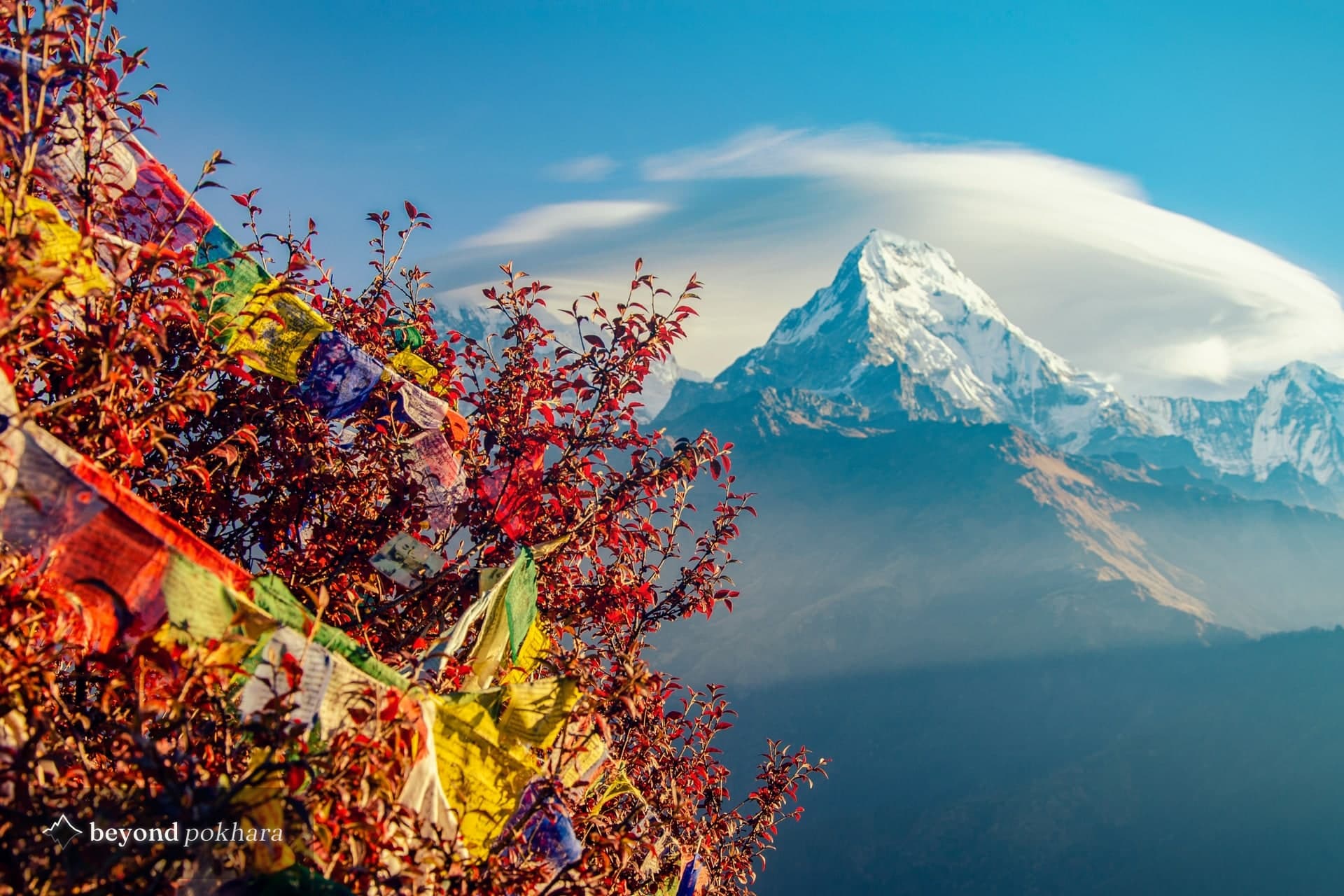 Annapurna South and prayer flags from Poon Hill under a clear autumn sky, the best time to visit Nepal for mountain views