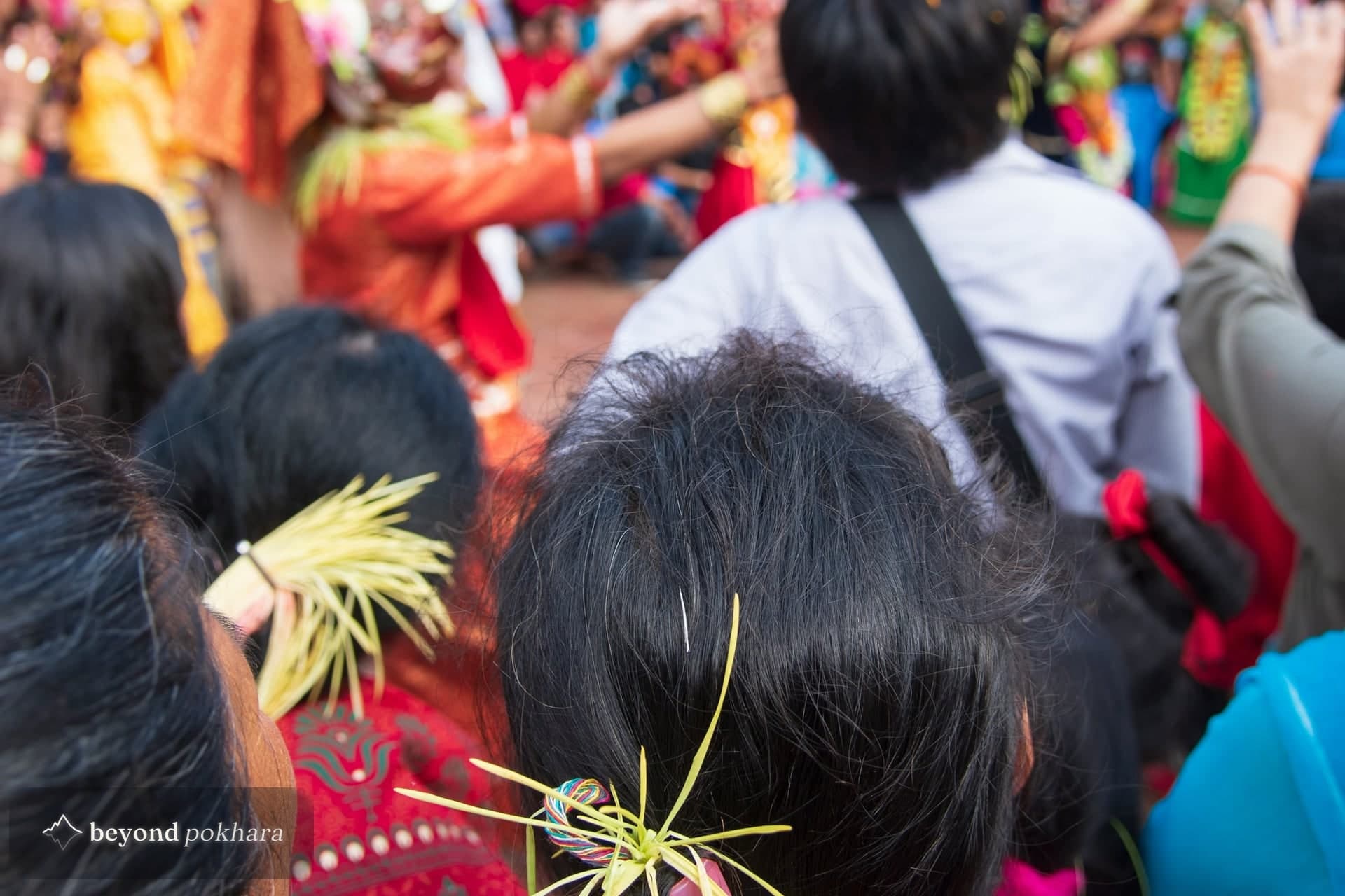 Women wearing jamara barley shoots in their hair watch masked dancers in Patan, a scene anyone travelling in Nepal during Dashain may come across